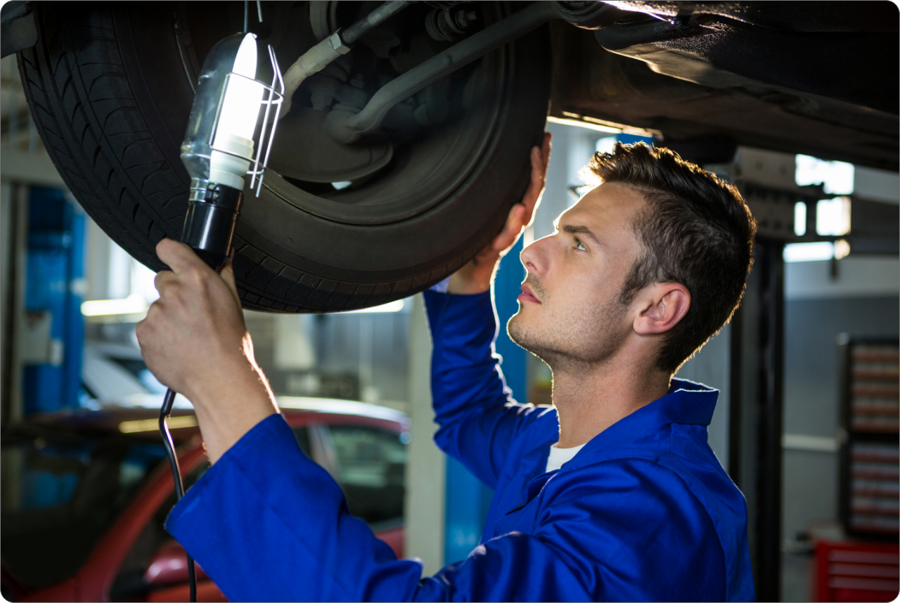mechanic-examining-car-tyre-using-flashlight